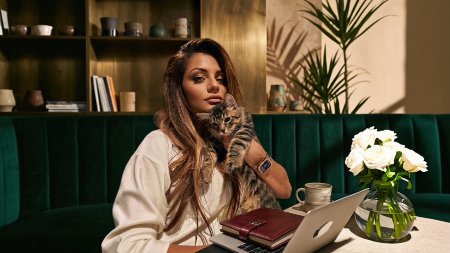 Lissette Arias at a laptop, holding a foster kitten